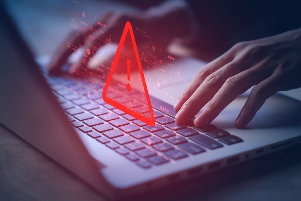 Mani che digitano su una tastiera con simbolo di allarme al centro